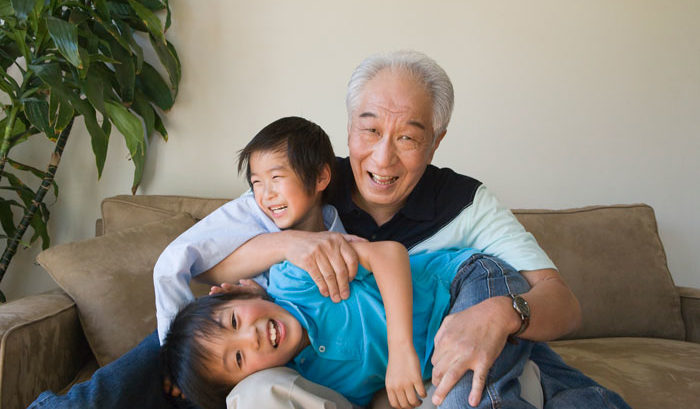 elderly asian man playing with grand kids in living room