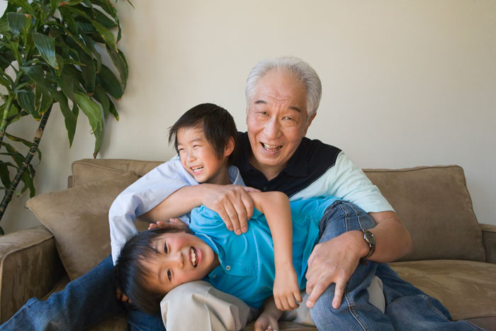 elderly asian man playing with grand kids in living room